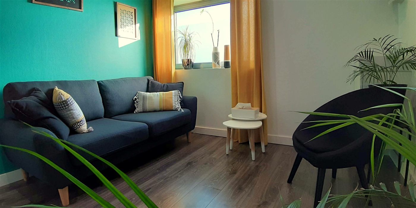 Salle de consultation avec canapé bleu et mur vert